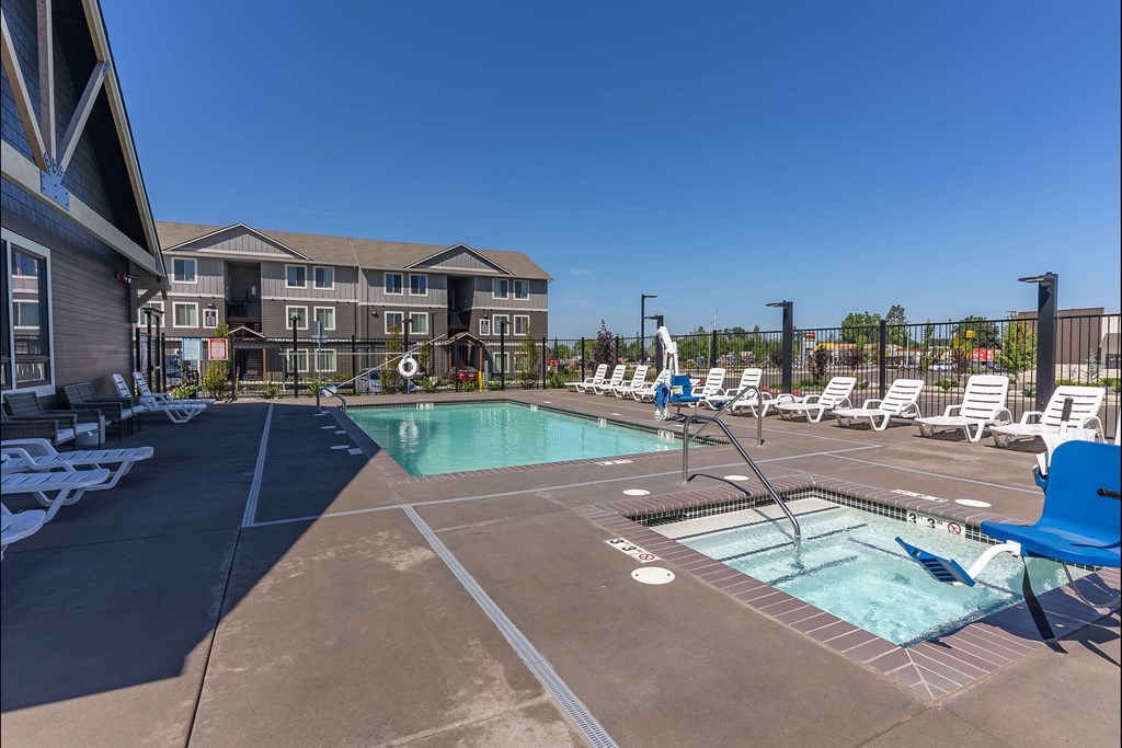 A large outdoor swimming pool with lounge chairs and a building in the background at Cascade Place Apartment Homes, Oregon