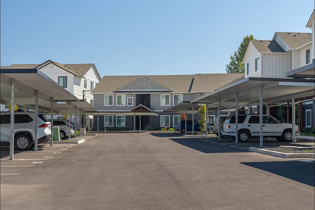 A parking lot with cars and a building in the background at Cascade Place Apartment Homes, Molalla