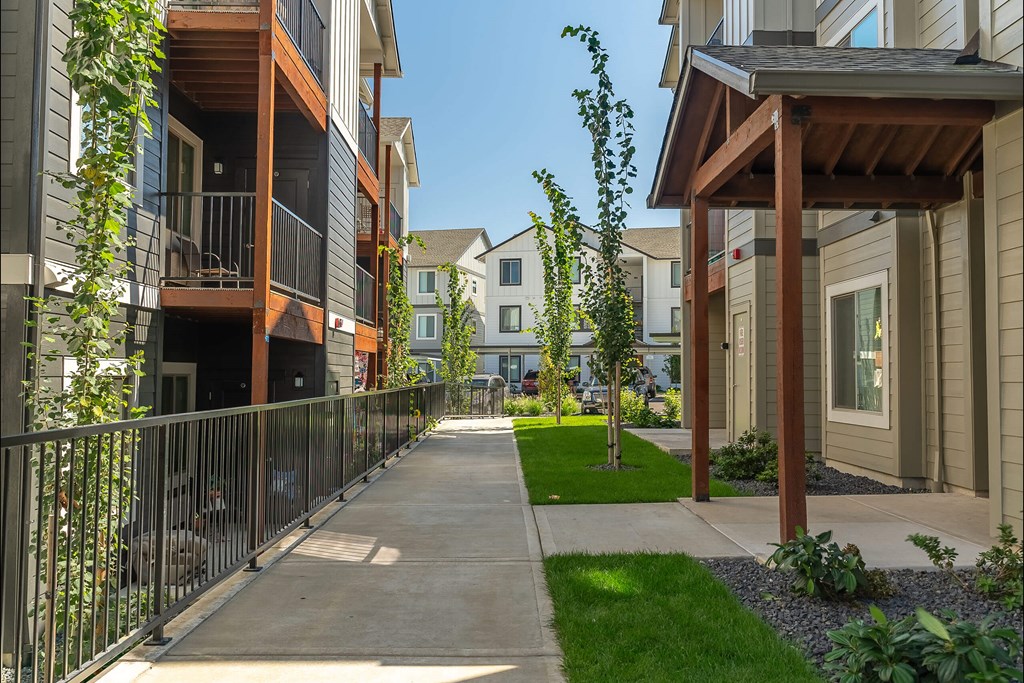 A row of townhouses with a sidewalk and greenery at Cascade Place Apartment Homes, Oregon, 97038