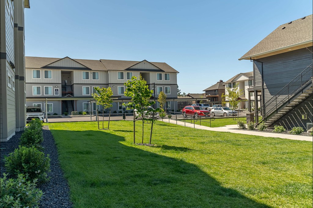 A red car is parked in a parking lot in front of a building at Cascade Place Apartment Homes, Molalla, OR