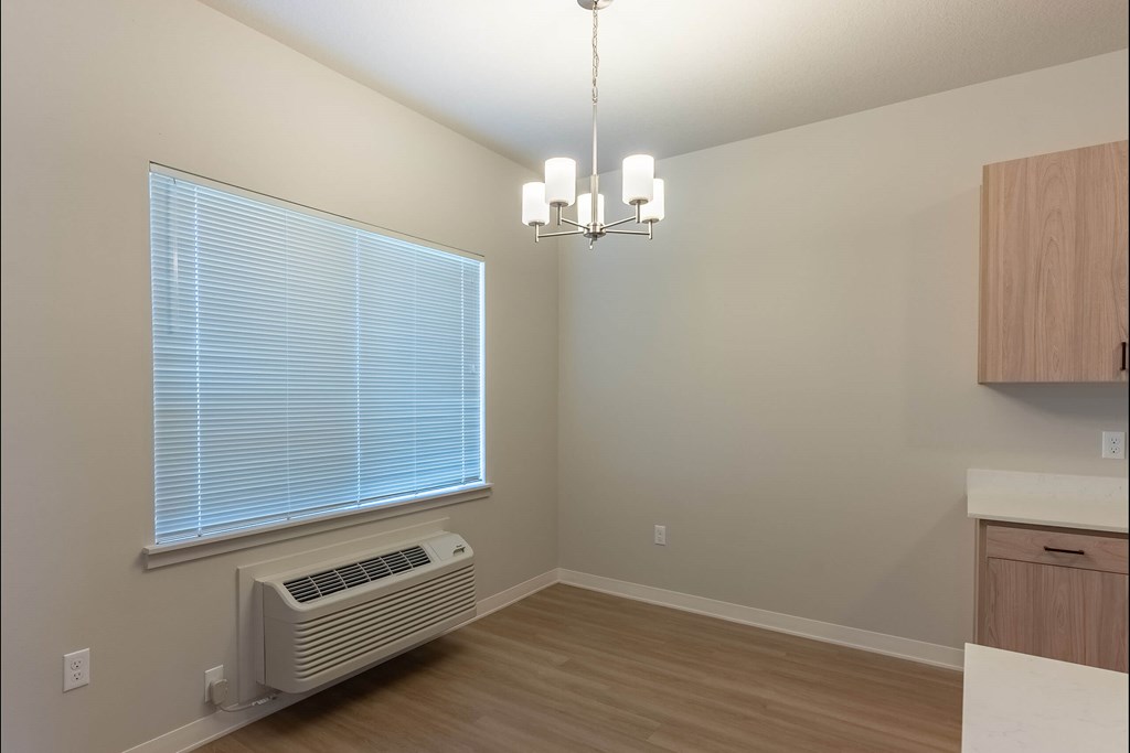 A room with a window, a chandelier, and a wall-mounted air conditioner at Cascade Place Apartment Homes, Molalla, 97038