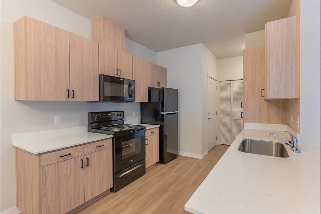 A kitchen with wooden cabinets and black appliances at Cascade Place Apartment Homes, Molalla, Oregon
