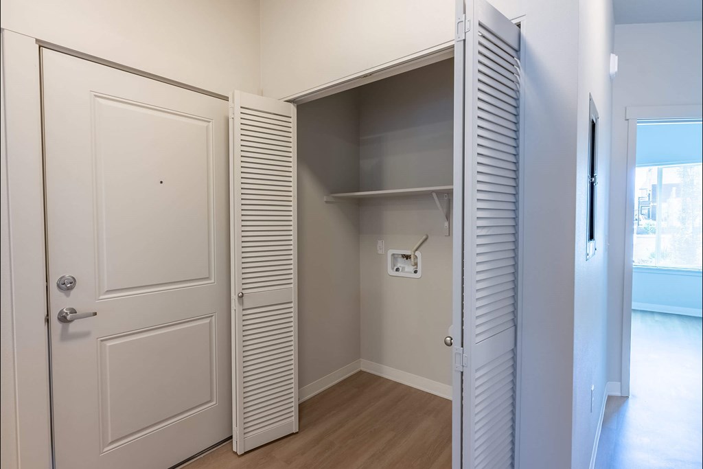 A white door is open to a small closet with shelves at Cascade Place Apartment Homes, Molalla