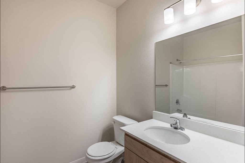 A white toilet sits next to a sink in a small bathroom at Cascade Place Apartment Homes, Oregon