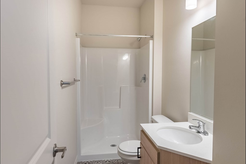 A white bathroom with a toilet, sink, and shower at Cascade Place Apartment Homes, Oregon