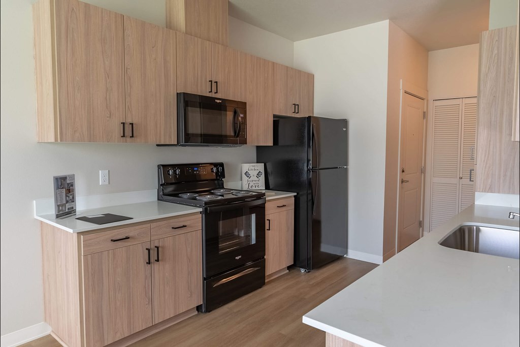 A kitchen with wooden cabinets and black appliances at Cascade Place Apartment Homes, Molalla