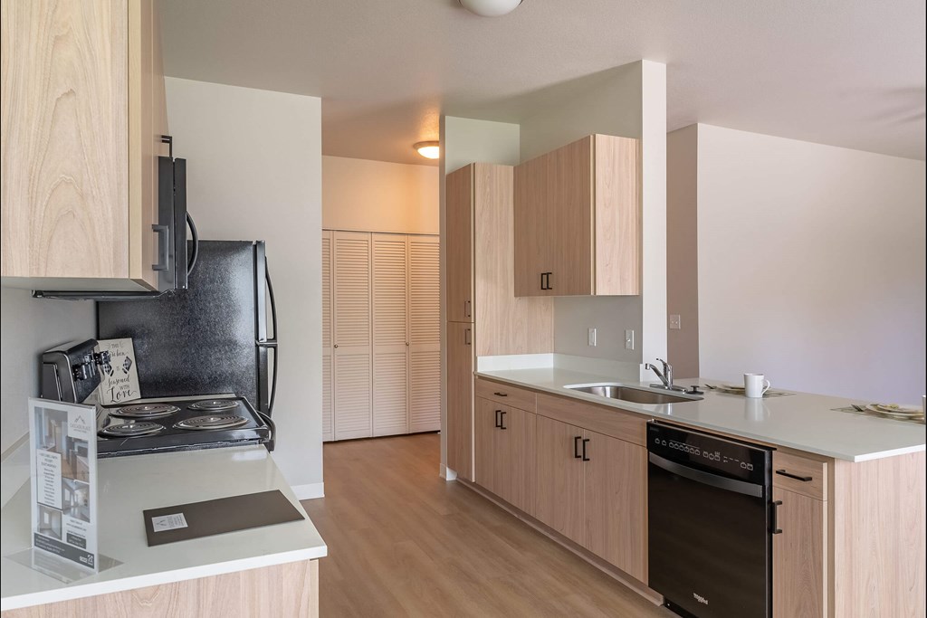 A kitchen with wooden cabinets and a black stove top at Cascade Place Apartment Homes, Molalla, OR, 97038