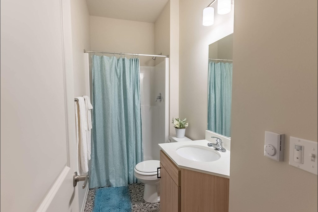 A bathroom with a toilet, sink, and shower curtain at Cascade Place Apartment Homes, Molalla, Oregon