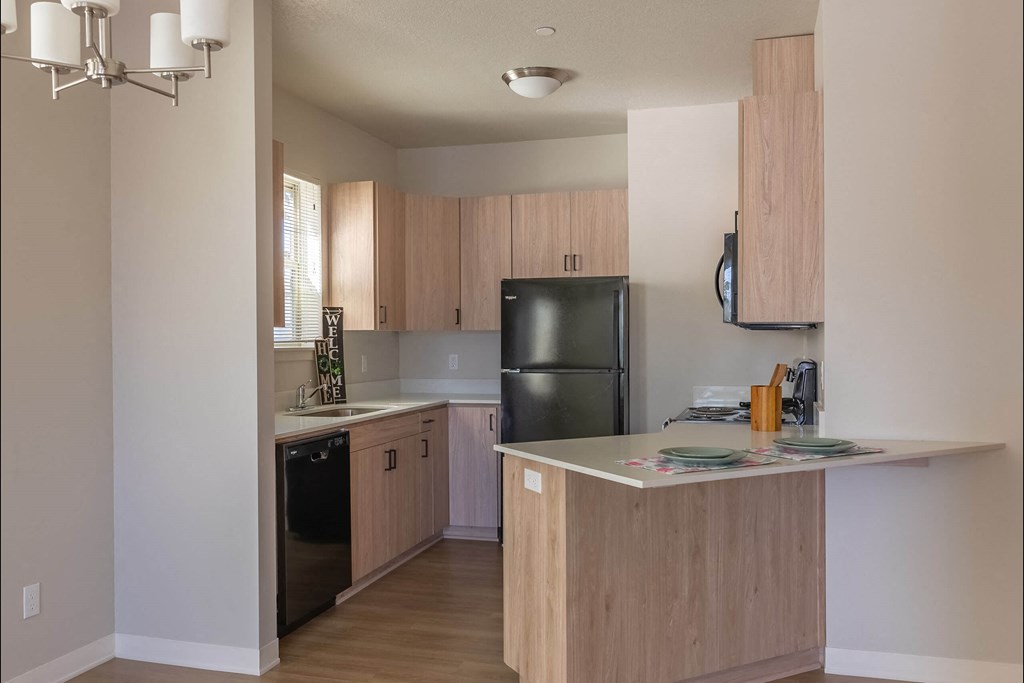 A kitchen with wooden cabinets and a black refrigerator at Cascade Place Apartment Homes, Oregon