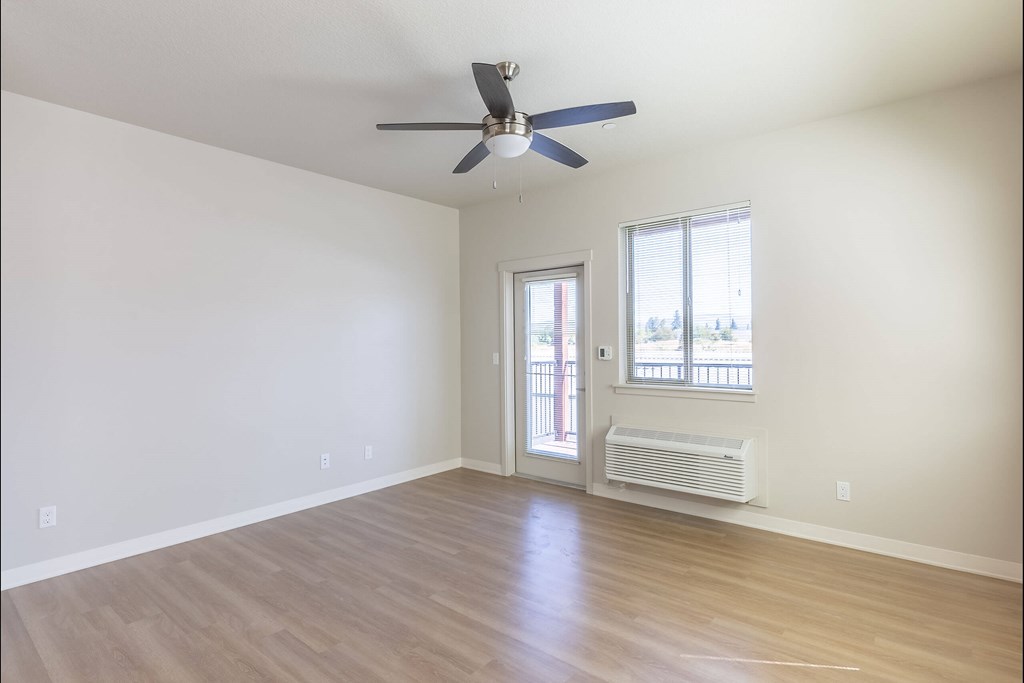A room with a ceiling fan and a window with a view of a balcony at Cascade Place Apartment Homes, Molalla