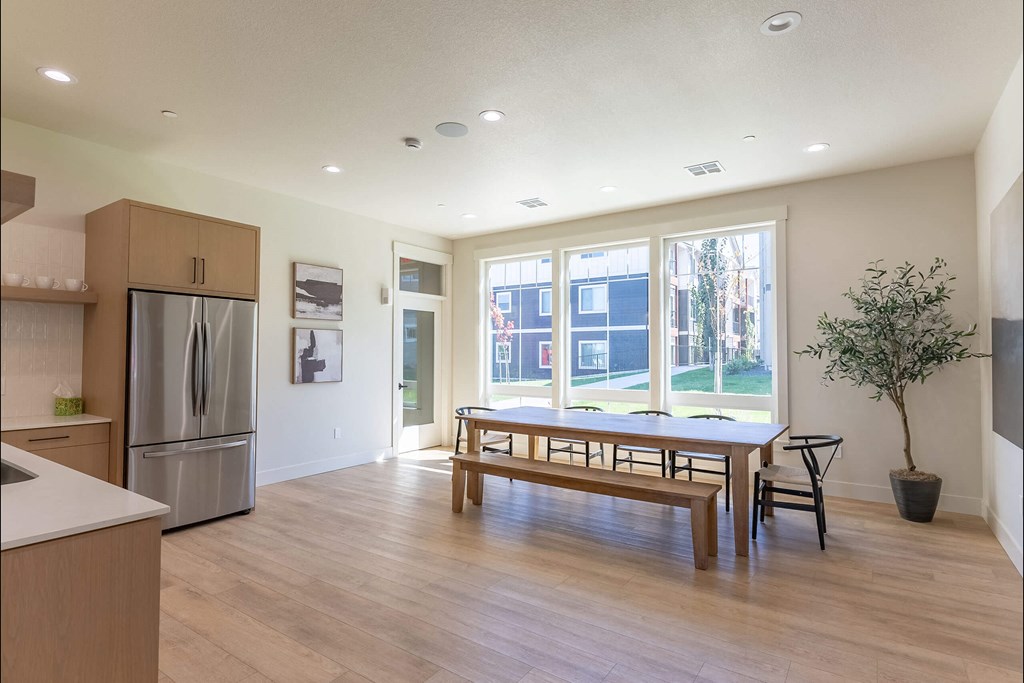 A kitchen with a refrigerator, a table and chairs, and a potted plant at Cascade Place Apartment Homes, Molalla, Oregon