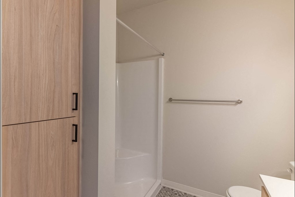 A white toilet sits in a small bathroom with a walk-in shower at Cascade Place Apartment Homes, Molalla