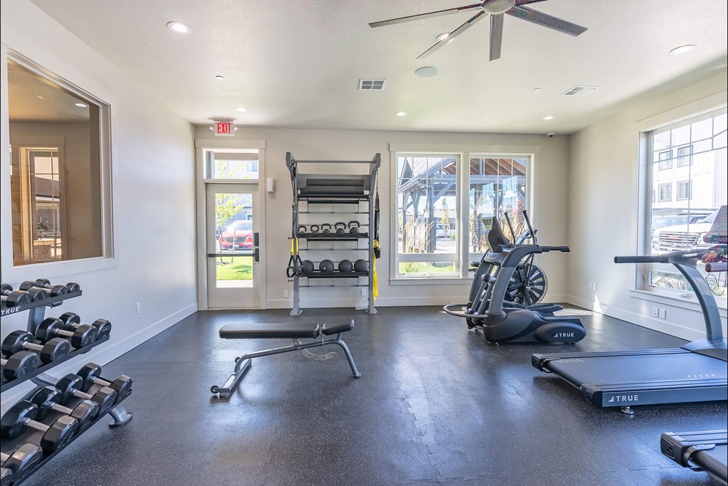 A gym with a treadmill, weights, and a bench at Cascade Place Apartment Homes, Molalla, Oregon