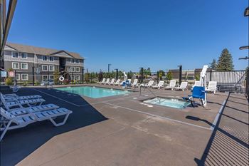 A pool area with sun loungers and a building in the background.