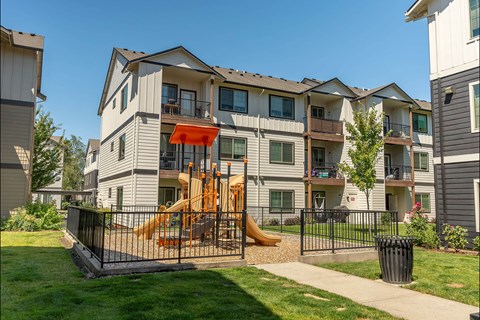 A playground with a slide is in front of a building at Forestplace Apartment Homes, Oregon