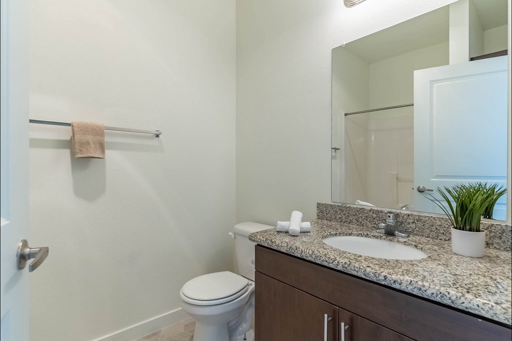 A bathroom with a toilet, sink, and mirror at Riverplace Apartment Homes, Independence, Oregon