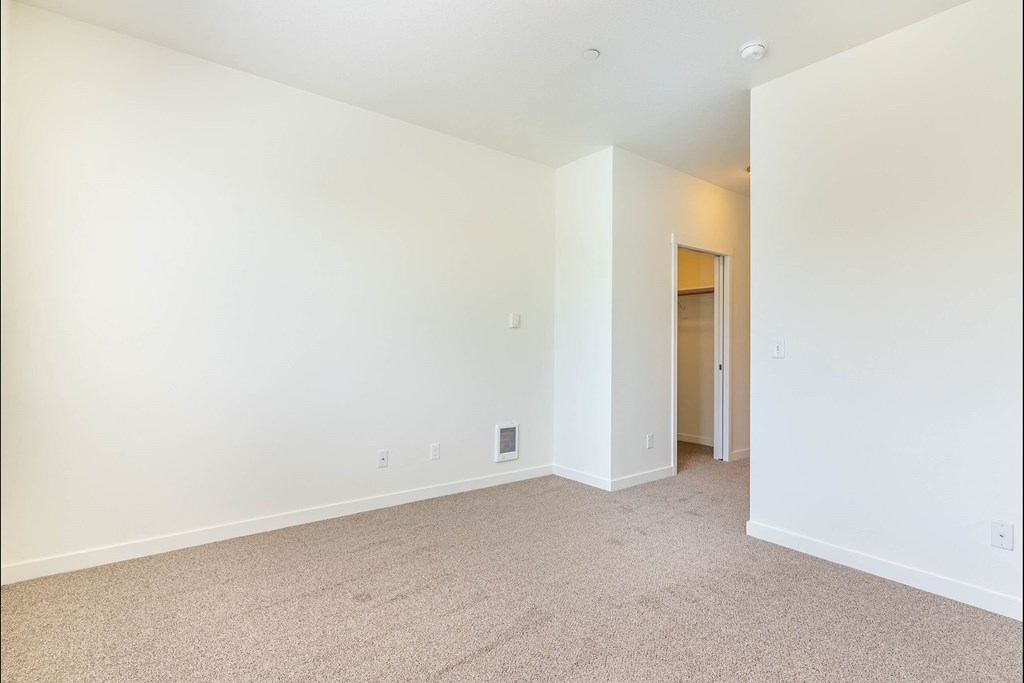 A large, empty room with carpeted flooring and white walls at Riverplace Apartment Homes, Oregon