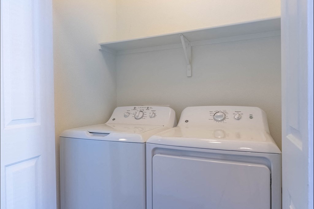 Two white front loading washing machines in a small laundry room at Riverplace Apartment Homes, Independence