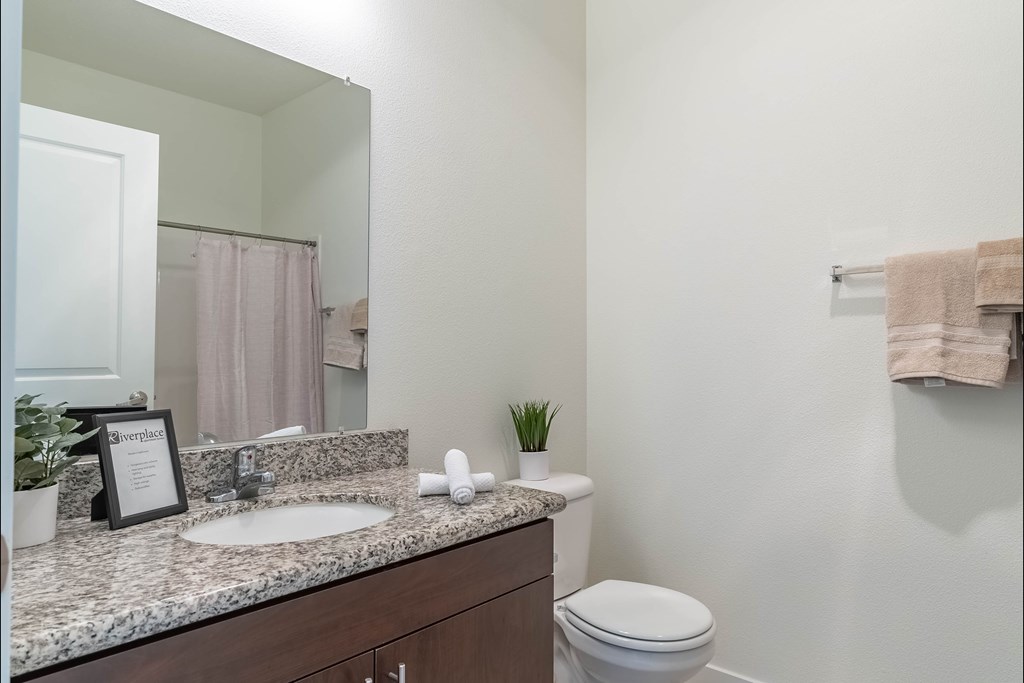 A bathroom with a white toilet and a marble counter top at Riverplace Apartment Homes, Independence, Oregon