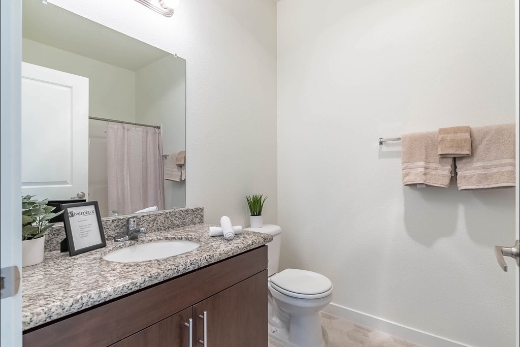 A bathroom with a toilet, sink, and mirror at Riverplace Apartment Homes, Independence, OR