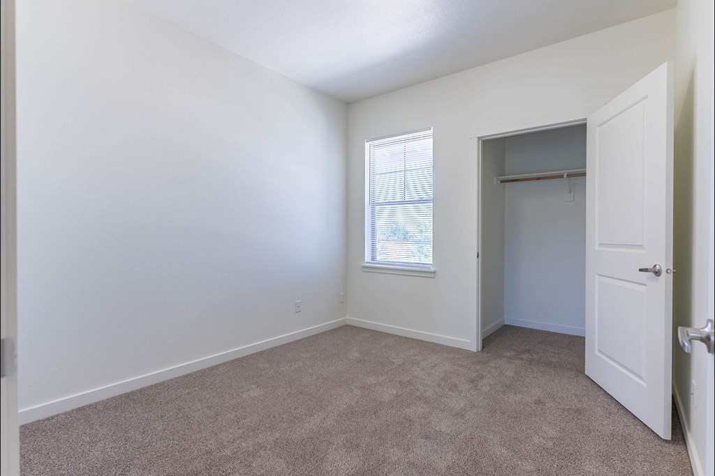 A room with a carpeted floor and a window with blinds at Riverplace Apartment Homes, Independence, OR
