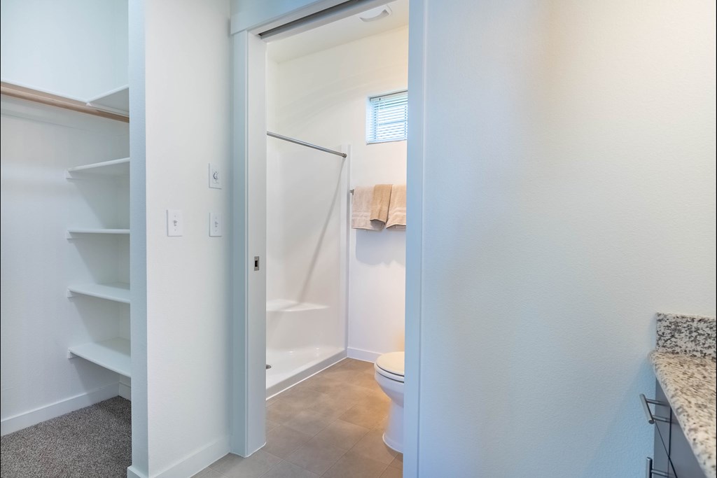 A white bathroom with a towel hanging on the door at Riverplace Apartment Homes, Oregon
