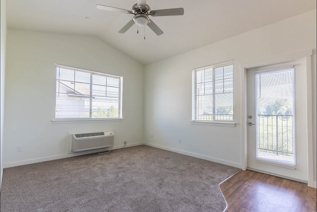 A room with a ceiling fan and two windows at Riverplace Apartment Homes, Independence