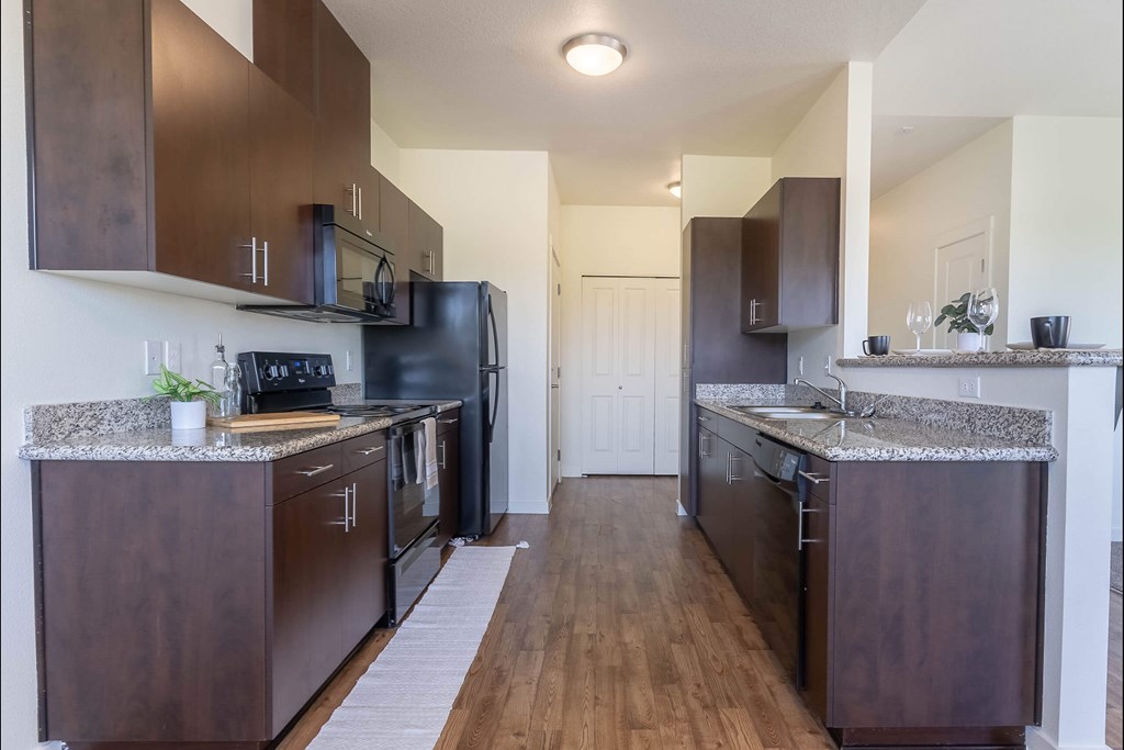 A kitchen with dark wood cabinets and a granite countertop at Riverplace Apartment Homes, Independence, Oregon