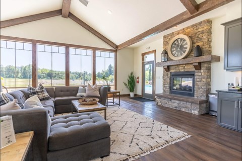 A living room with a grey couch and a stone fireplace.