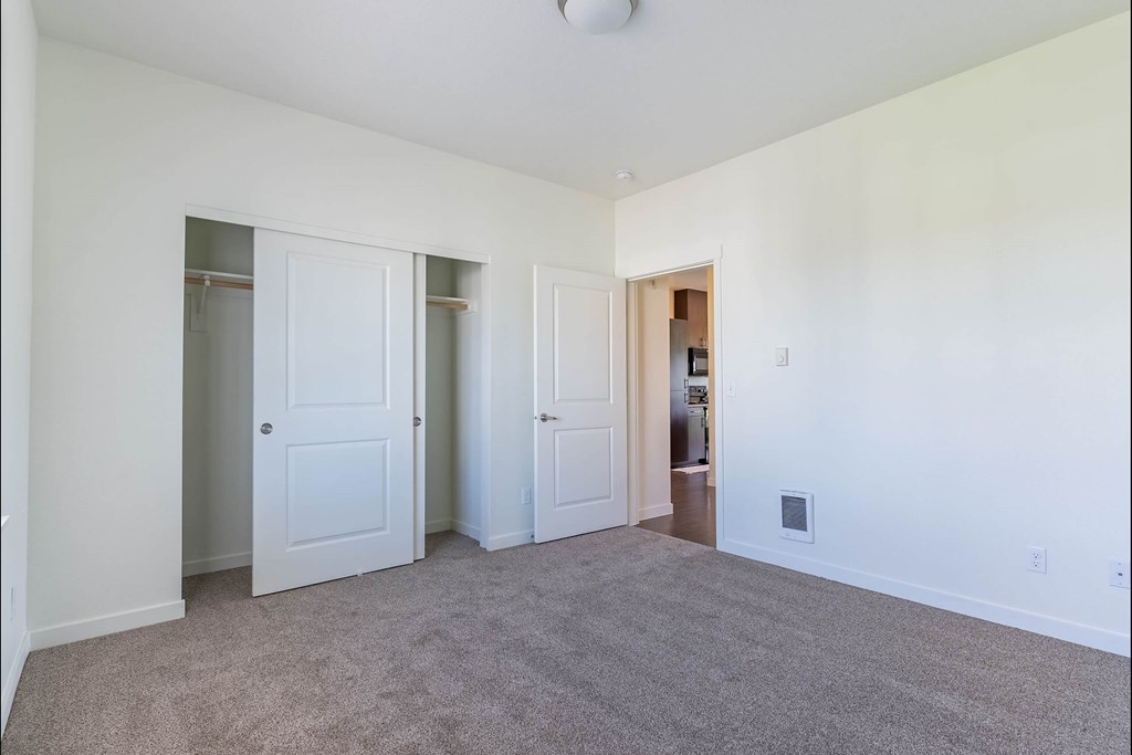 A room with carpeted floor and white walls with a doorway leading to another room at Riverplace Apartment Homes, Independence, 97351