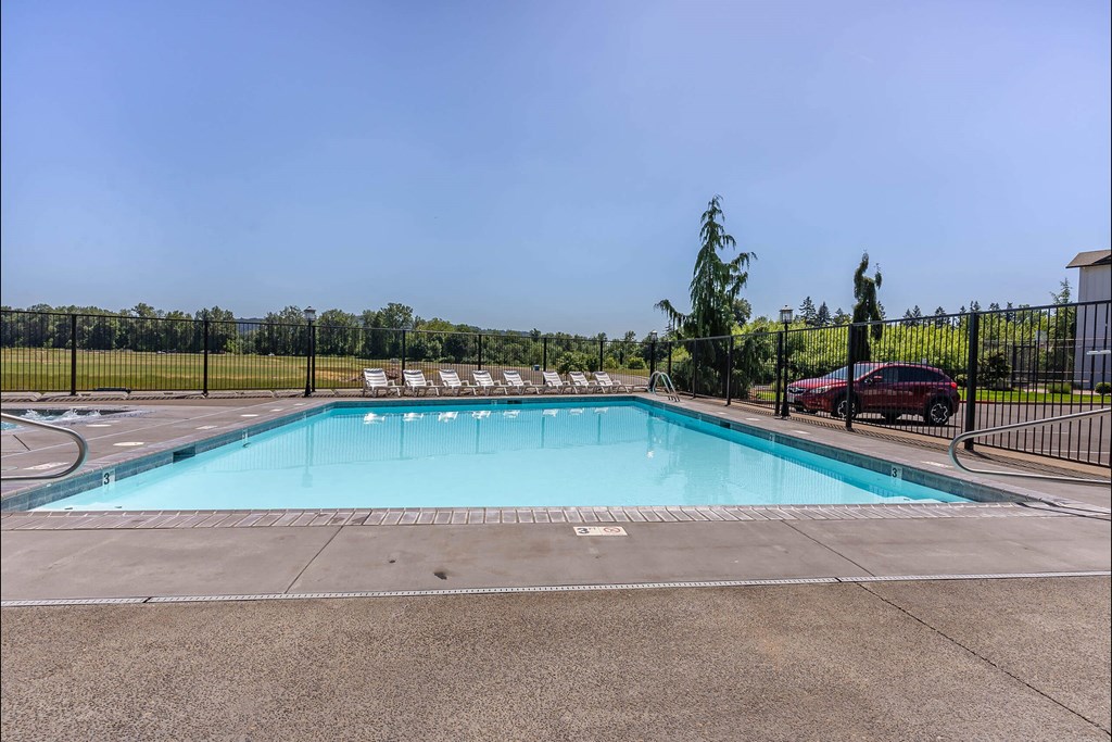 A large outdoor swimming pool surrounded by a fence at Riverplace Apartment Homes, Independence