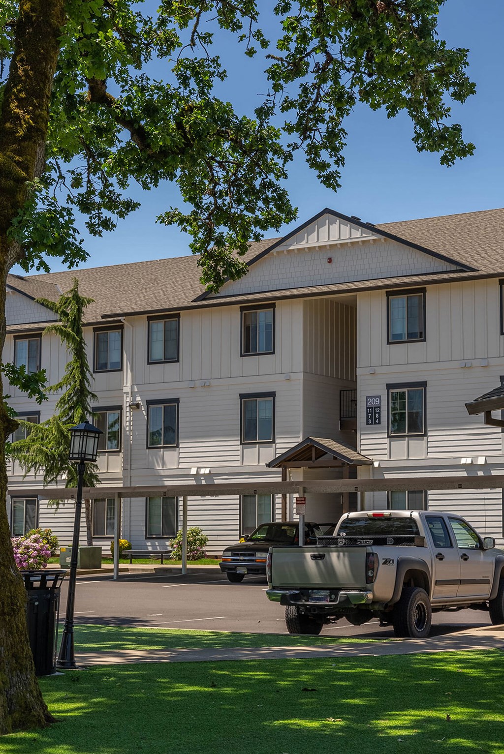 A large white building with a brown roof and a truck parked in front at Riverplace Apartment Homes, Independence, OR