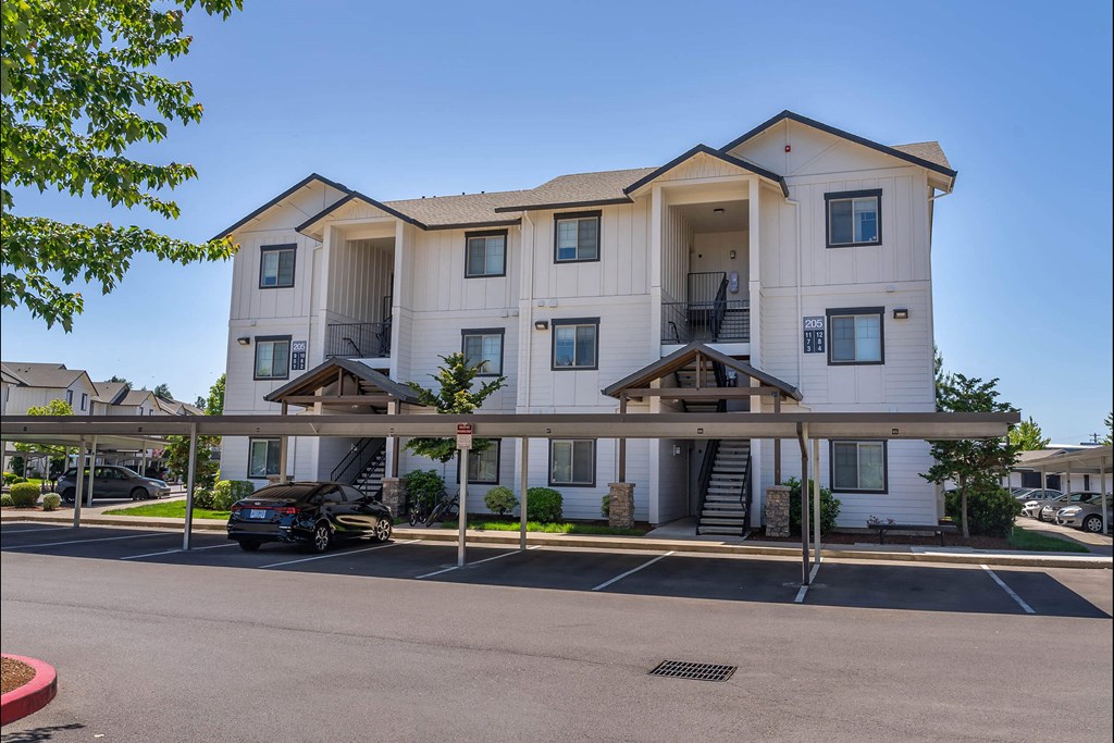 A large white apartment building with a car parked in front at Riverplace Apartment Homes, Oregon, 97351