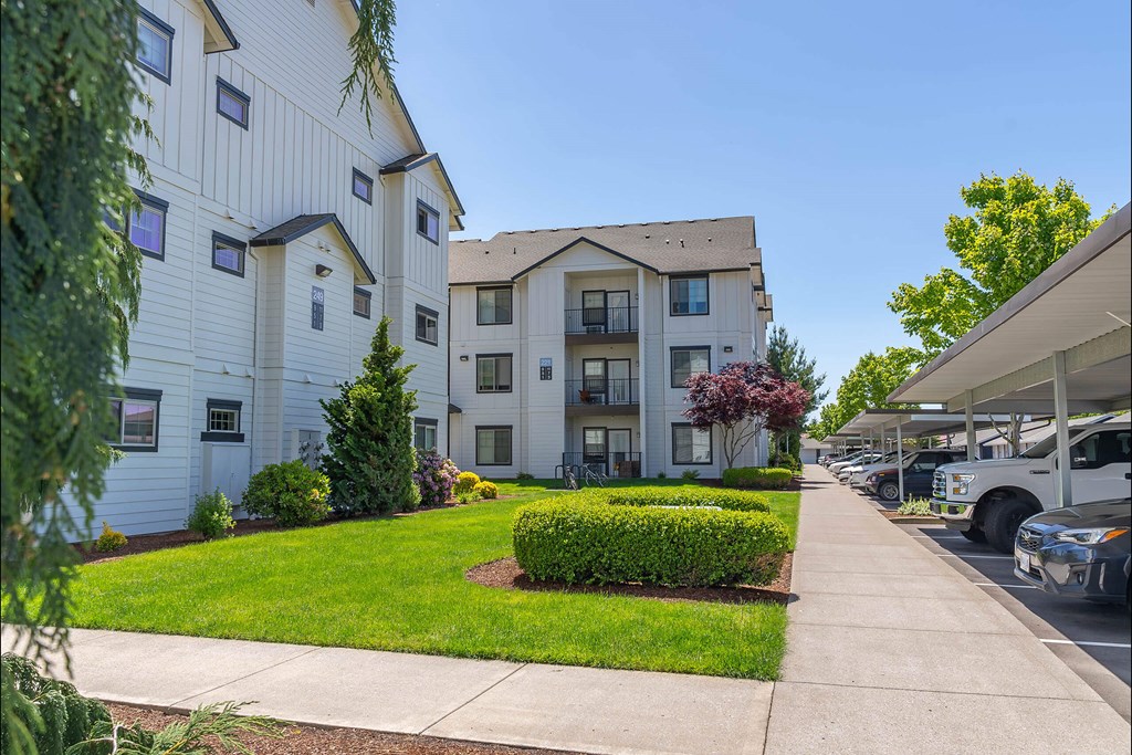 A white apartment building with a green lawn in front at Riverplace Apartment Homes, Independence, OR