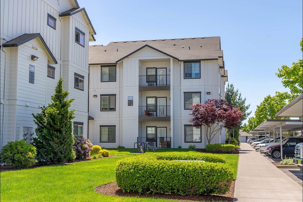 A white apartment building with a green lawn in front at Riverplace Apartment Homes, Independence, OR, 97351