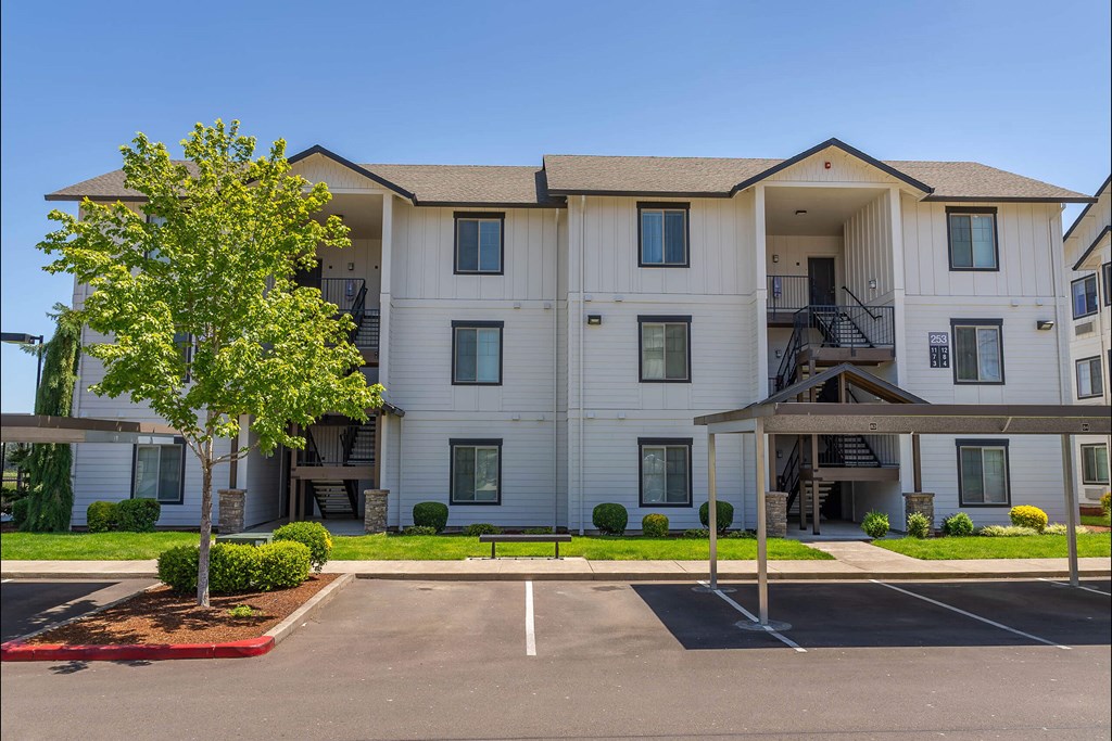 A large white apartment building with a tree in front at Riverplace Apartment Homes, Independence, Oregon