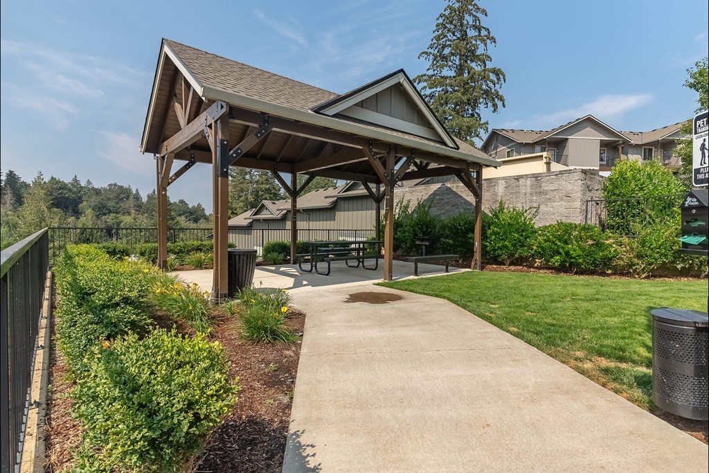 A covered picnic area with a bench and a trash can at Sandyplace Apartment Homes, Sandy, 97055