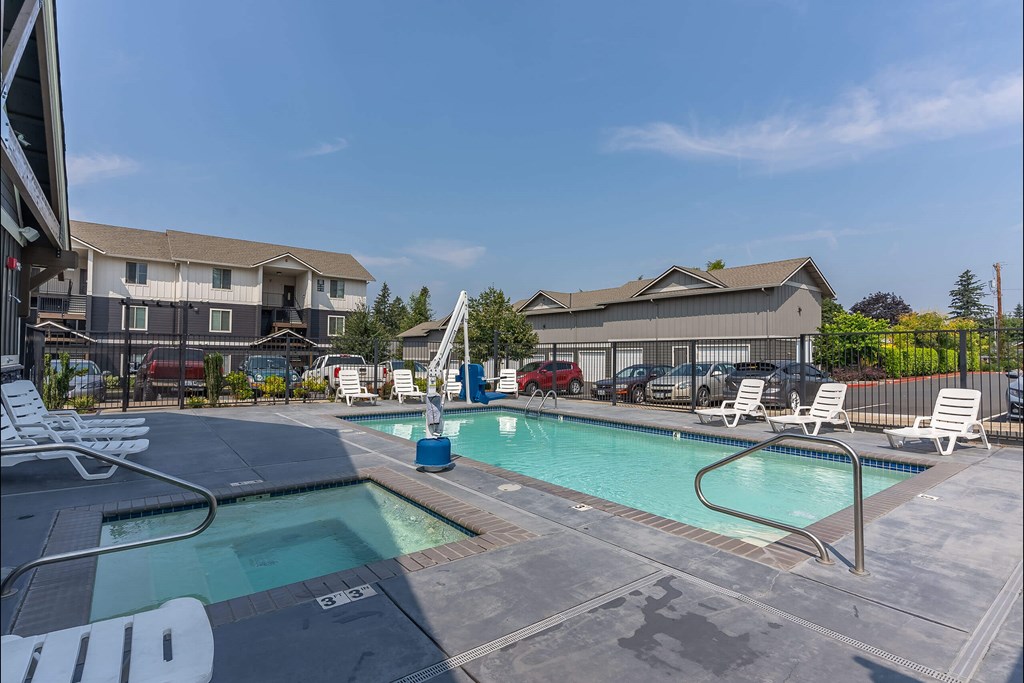 A swimming pool with a slide and lounge chairs at Sandyplace Apartment Homes, Oregon
