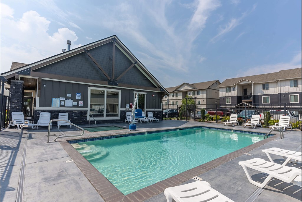 A pool area with a house and chairs at Sandyplace Apartment Homes, Sandy, 97055