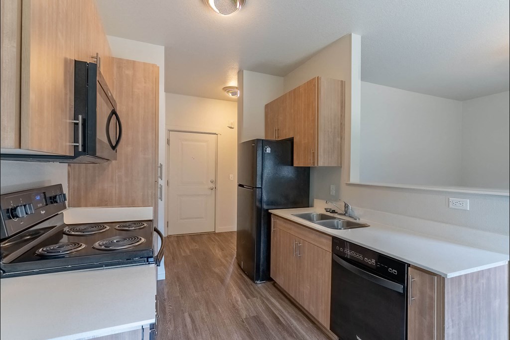 A kitchen with black appliances and wooden cabinets at Sandyplace Apartment Homes, Oregon