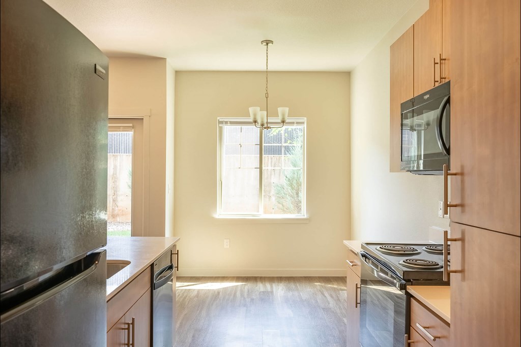 A kitchen with wooden cabinets and a stainless steel refrigerator at Sandyplace Apartment Homes, Sandy, Oregon