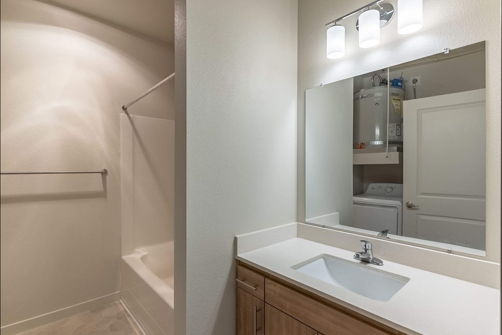A bathroom with a sink, mirror, and shower at Sandyplace Apartment Homes, Oregon
