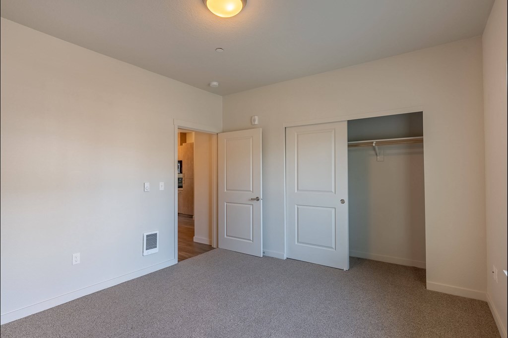 A room with a carpeted floor and a white door at Sandyplace Apartment Homes, Oregon