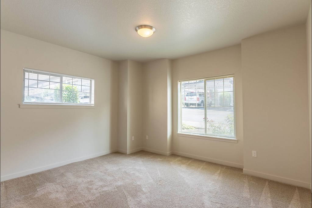 A spacious room with two windows and carpeted floor at Sandyplace Apartment Homes, Sandy, Oregon