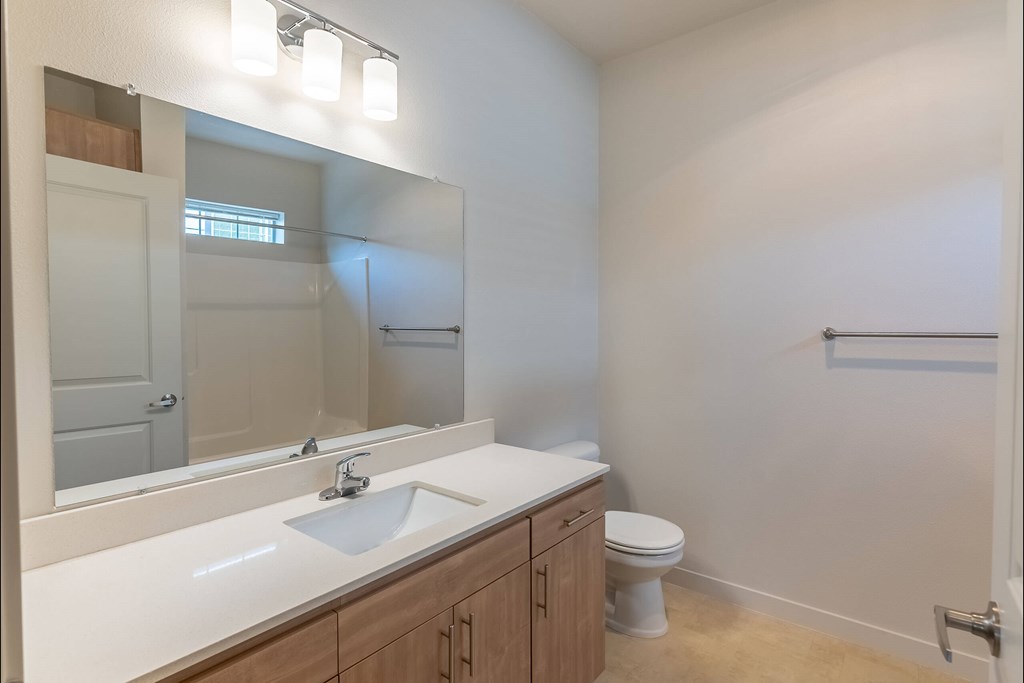A bathroom with a sink, toilet, and mirror at Sandyplace Apartment Homes, Sandy, OR, 97055