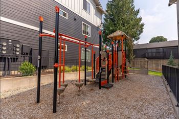 A playground with a red swing set and a black fence.