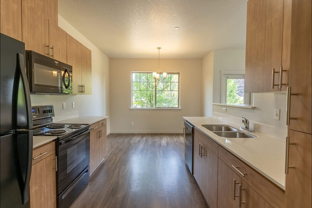 A kitchen with wooden cabinets and a black refrigerator at Sandyplace Apartment Homes, Sandy