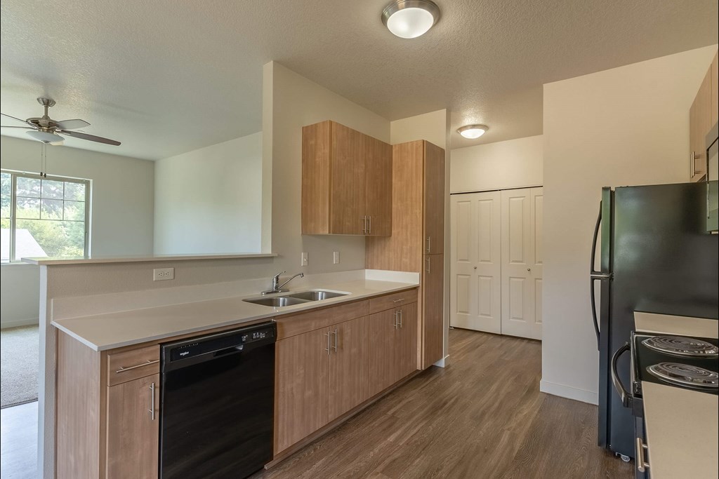 A kitchen with wooden cabinets and a black dishwasher at Sandyplace Apartment Homes, Sandy, OR, 97055