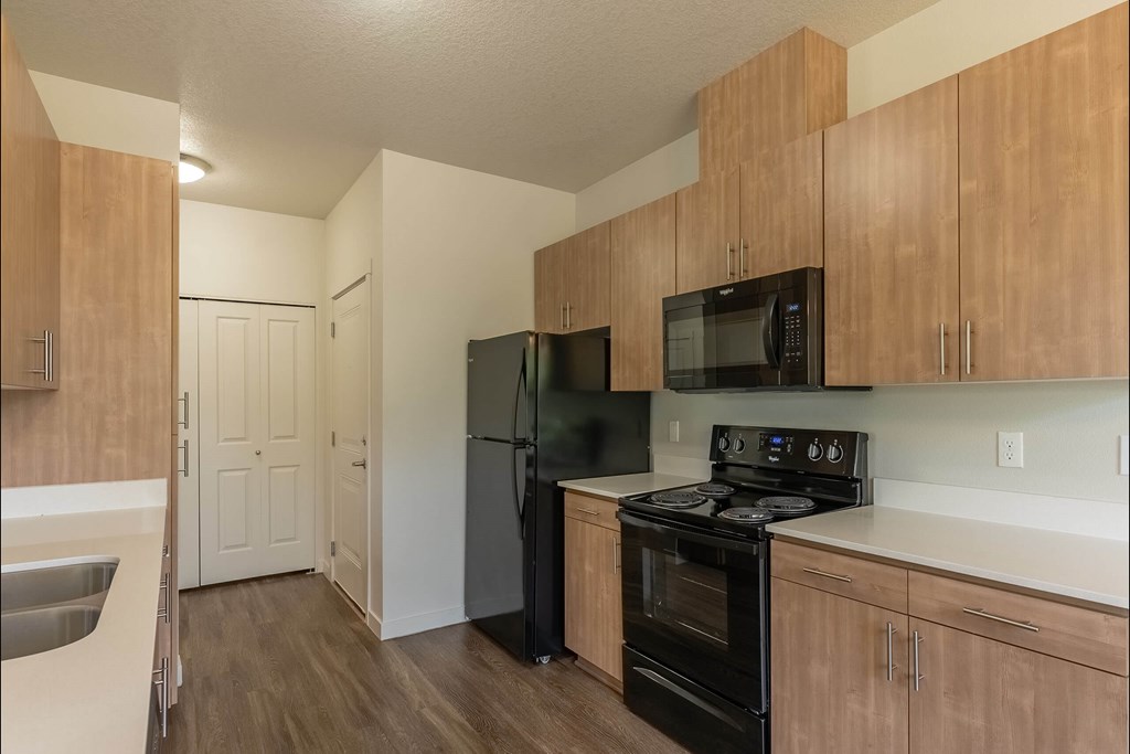 A kitchen with black appliances and wooden cabinets at Sandyplace Apartment Homes, Oregon, 97055