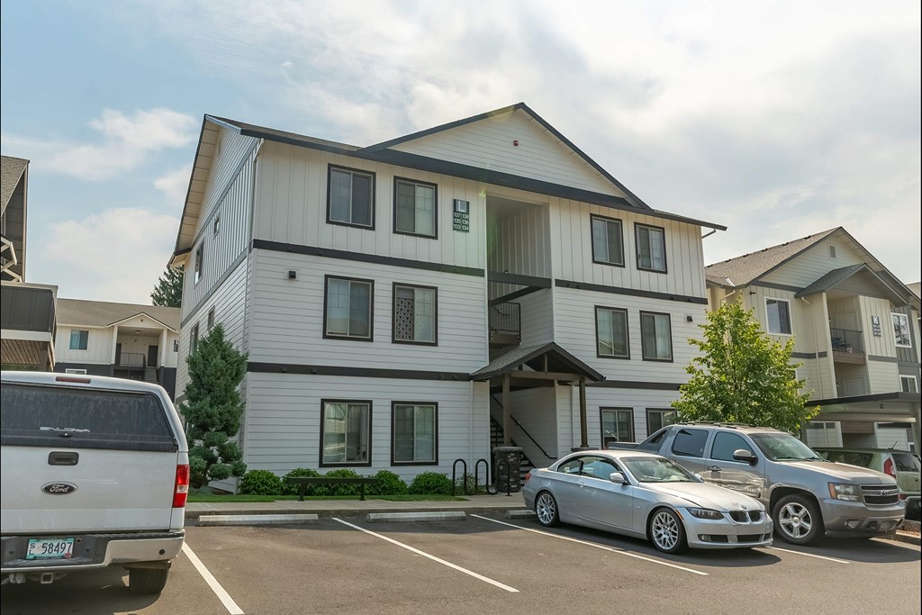 A white two-story building with a parking lot in front at Sandyplace Apartment Homes, Sandy, OR